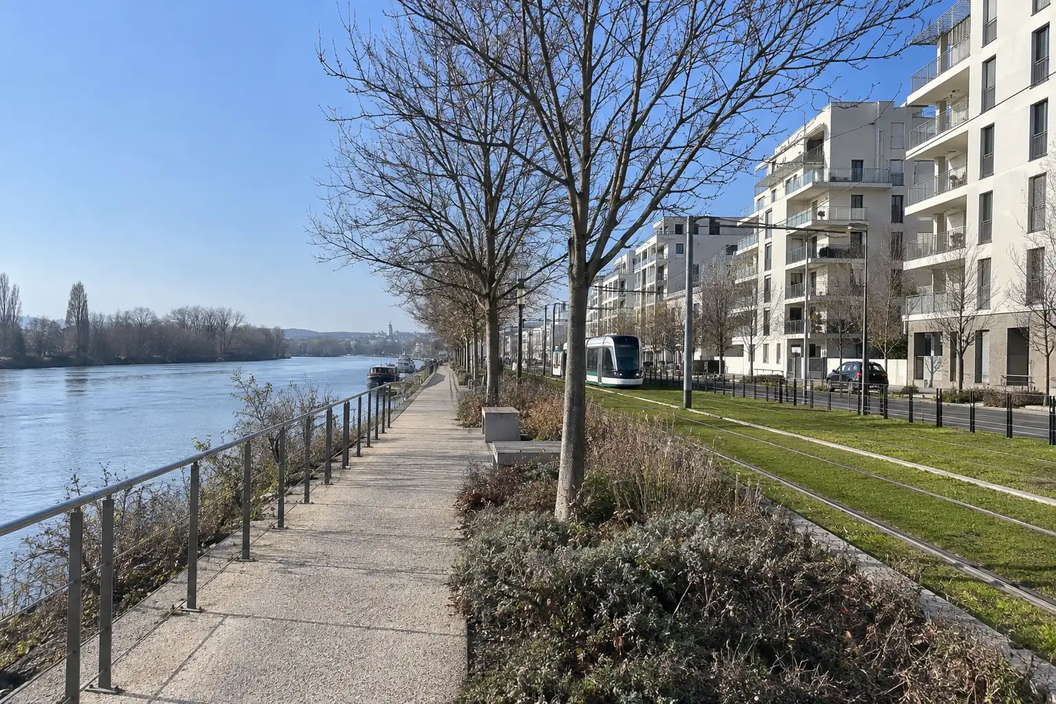 Promenade au bord de la Seine, immeubles récents aux façades claires et voie de tramway, par un matin d’hiver dégagé
