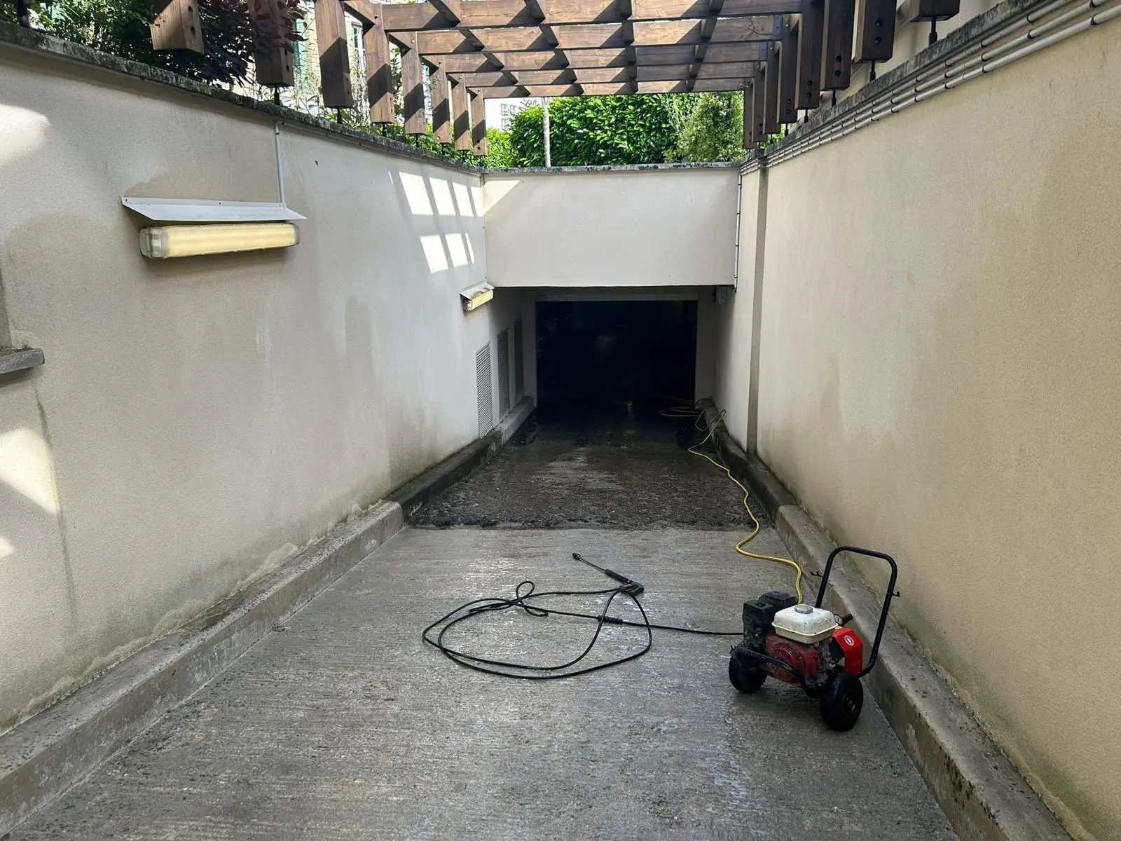 Nettoyeur haute pression posé sur une rampe de parking, devant l’entrée du sous-sol