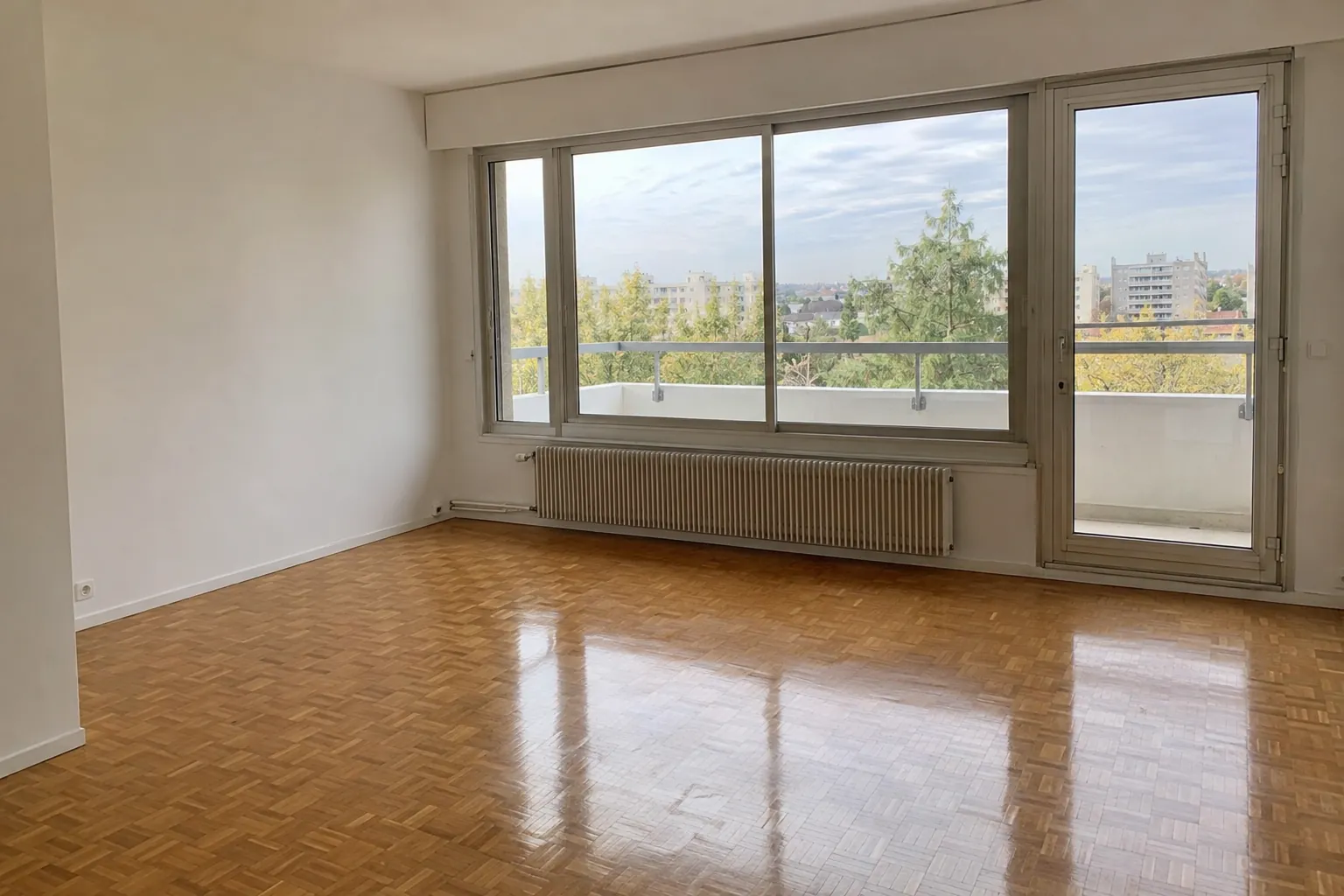 Séjour vide au parquet propre et aux vitres nettes, prêt pour une visite